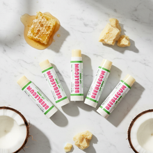 Load image into Gallery viewer, 5 Beeblegum Lip Care balm sticks fanned out with beeswax and coconut on white marble